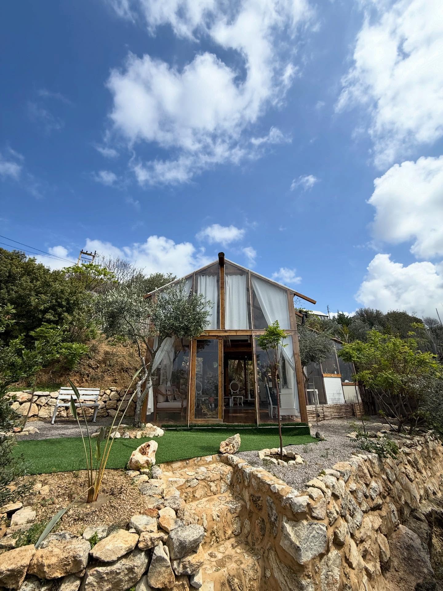 A-frame glass cabin surrounded by Mediterranean landscape